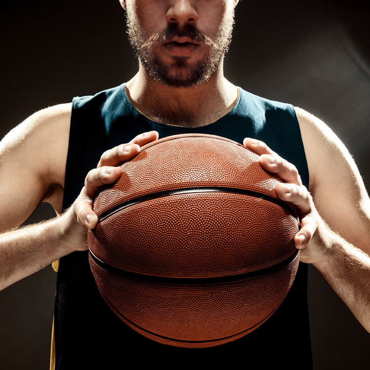 The silhouette view of a basketball player holding basket ball on black background. The hands and ball close up